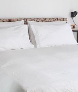 un letto bianco con lenzuola e cuscini bianchi di Flat and garage near Rho-FieraMilano-MIND-Galeazzi a Pero