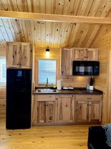 een keuken met houten kasten en een zwarte koelkast bij 2 Bedroom Log Cabin on Lake James with Loft- Private Resort Amenities in Marion