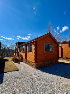een blokhut met een veranda en een huis bij 2 Bedroom Log Cabin on Lake James with Loft- Private Resort Amenities in Marion