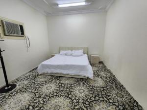a white bedroom with a bed and a rug at شقة طيبه المدينة 5 in Al Madinah