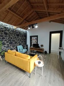 a yellow couch in a living room with a stone wall at Casa do Poço in Santa Bárbara