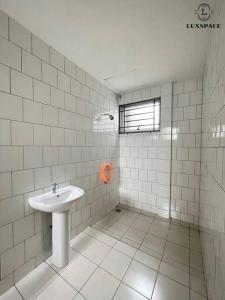 a white tiled bathroom with a sink and a window at Cozy Kuching Samarahan Townhouse in Kota Samarahan