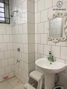 a white bathroom with a sink and a mirror at Cozy Kuching Samarahan Townhouse in Kota Samarahan