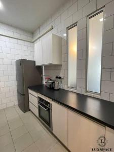 a kitchen with a black counter top and a refrigerator at Cozy Kuching Samarahan Townhouse in Kota Samarahan