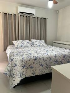 Schlafzimmer mit einem Bett mit einer blauen und weißen Bettdecke in der Unterkunft Chacara casa de campo Condomínio fechado itupeva in Itupeva