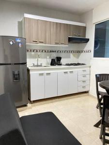 a kitchen with white cabinets and a stainless steel refrigerator at Apartamento cómodo cerca al aeropuerto in Cartagena de Indias