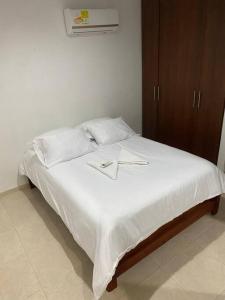 Una cama con sábanas blancas y dos cruces. en Apartamento cómodo cerca al aeropuerto en Cartagena de Indias