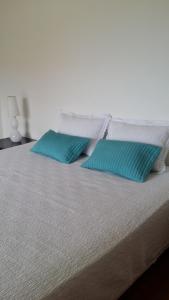 Una cama con dos almohadas azules. en Casa do Baleal, en Baleal