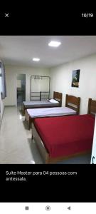um quarto com três camas num quarto em Chácara Rosa do Deserto em Vila Velha