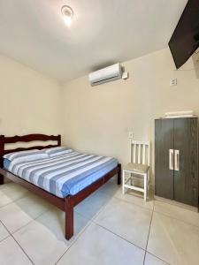 1 dormitorio con 1 cama y TV. en MORADA GARAPEIRA, en Guarda do Embaú