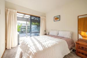 a bedroom with a bed and a large window at Oneroa Spa Retreat- Waiheke Escapes in Blackpool