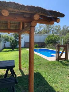 a wooden pergola with a bench next to a pool at Hospedaje El Ciruelo in Alta Gracia