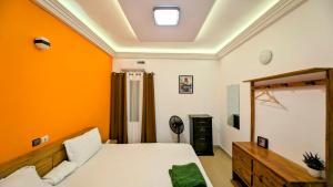 um quarto com paredes cor-de-laranja, uma cama e um espelho. em Timba-Pekin em Cotonou