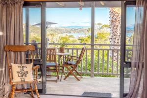 d'un balcon avec des chaises et une table munie d'un panneau. dans l'établissement Oneroa Spa Retreat- Waiheke Escapes, à Blackpool