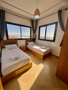 Baya House Sea View في أغادير: غرفة نوم بسريرين ونوافذ