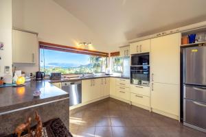 a kitchen with white cabinets and a large window at Oneroa Spa Retreat- Waiheke Escapes in Blackpool