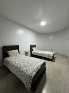 deux lits dans une chambre aux murs blancs dans l'établissement Darna surf, à Agadir