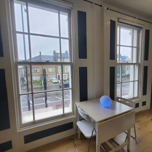 a room with a table and two large windows at London Oasis Studio Apartment in London