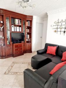 a living room with a black couch and a television at Hermosa casa en Bucaramanga in Bucaramanga