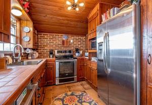 La cuisine est équipée d'armoires en bois et d'un réfrigérateur en acier inoxydable. dans l'établissement Canary's Nest, à Hot Springs