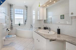 baño blanco con bañera, lavabo y aseo en Villa Linde FeWo 4, en Ahlbeck