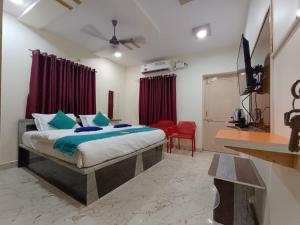 a bedroom with a bed and a red chair at J Beach Stay Rooms in Visakhapatnam