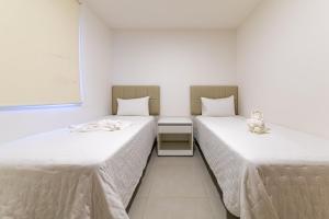 two beds in a room with white walls at Apto Póximo a Praia de Barra de São Miguel - Destino BSM 106 A in Barra de São Miguel +35 photos