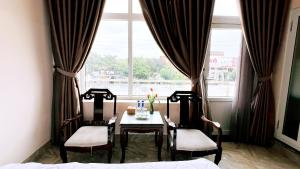 a dining room with a table and chairs in front of a window at Song Huong Hue Hotel in Hue