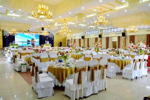 une salle de banquet avec des tables blanches, des chaises et des lustres dans l'établissement Song Huong Hue Hotel, à Hue