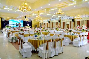 フエにあるSong Huong Hue Hotelの白いテーブルと椅子、シャンデリアのある宴会場