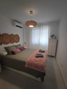 a bedroom with a bed with a pink blanket and a dresser at Apartamento Pilar in Seville