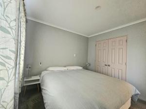 ein Schlafzimmer mit einem weißen Bett und einer weißen Tür in der Unterkunft Cozy Private Villa in Oropi in Oropi