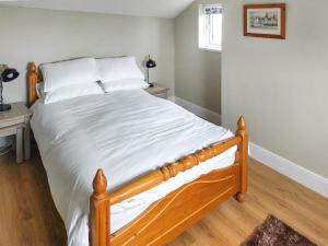 Una cama con sábanas blancas y almohadas en un dormitorio en The Lodge At Owstwick Hall 