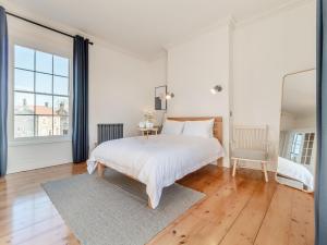 a white bedroom with a bed and a chair at Red House in Methwold