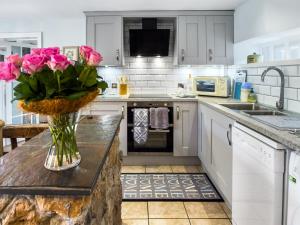 uma cozinha com um vaso de flores cor-de-rosa num balcão em Cherry Tree Cottage - Uk46659 em Cheddar