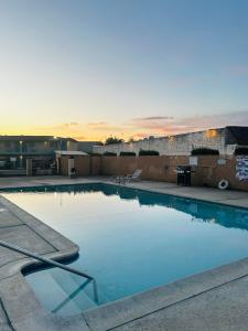 a swimming pool with a sunset in the background at Franciscan Inn Motel in Vista