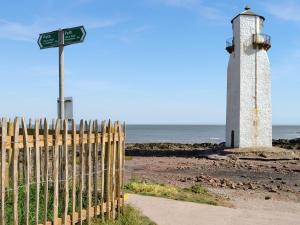 un faro en la playa junto a una valla en Kadelin Cove en Mainsriddle