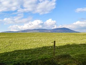 una valla en un campo con montañas en el fondo en Kadelin Cove en Mainsriddle