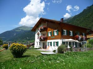 una casa en una colina con un barco en el patio en Ferienwohnung Brugger, en Sankt Gallenkirch