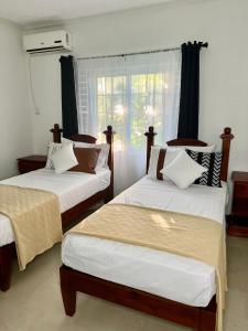 twee bedden in een kamer met een raam bij Ocho Rios Oasis in St Mary