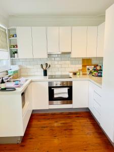 cocina con armarios blancos y fogones en Sunshine Retreat Modern 3BR Haven, en St Marys