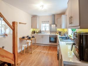 a large kitchen with white cabinets and a wooden floor at Mews Cottage in Abergele