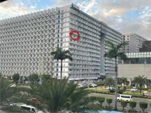 un gran edificio blanco con un reloj rojo. en Shell Residences by Amonbrey Suite nr airport, en Manila