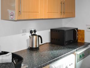 a kitchen counter with a coffee maker and a microwave at Coillessan Lodge in Inverkirkaig