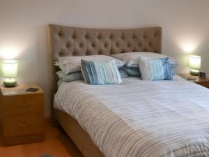 a bedroom with a large bed with pillows and two lamps at Coillessan Lodge in Inverkirkaig