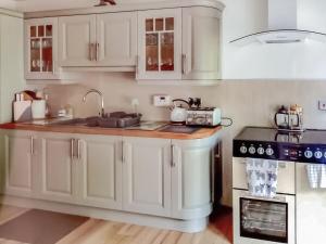 uma cozinha com armários brancos e um lavatório em Fishponds Cottage em Perth
