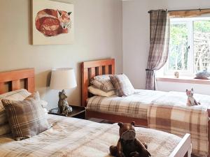 um quarto com duas camas e um bicho de peluche sentado na cama em Fishponds Cottage em Perth