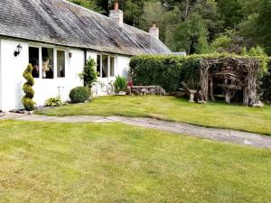 a white house with a grass yard in front of it at Fishponds Cottage in Perth