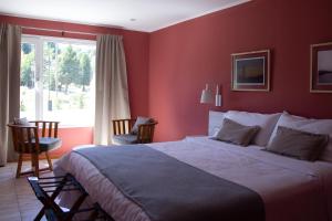 una camera da letto con un grande letto con pareti rosse di Hostería Las Semillas a Villa La Angostura