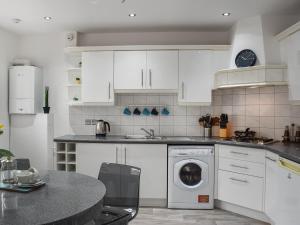 a kitchen with white cabinets and a washing machine at West Street House in Southport